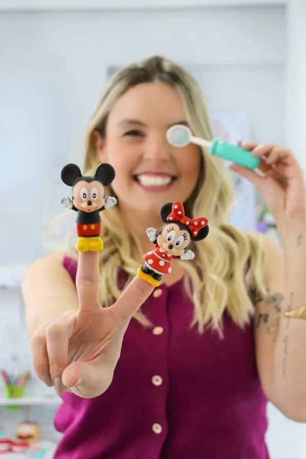 Dra. Juliana Lozano usando brinquedos de dedo e um espelho odontológico colorido para deixar a consulta infantil mais leve